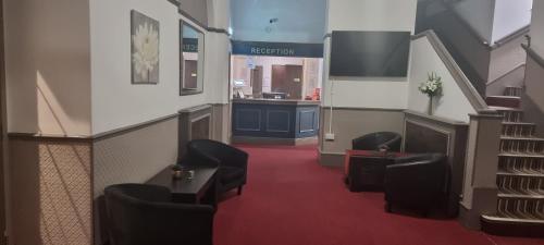 een wachtkamer met stoelen en een trap bij Midlands Hotel in Mansfield