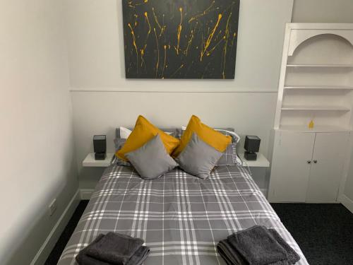 a bedroom with a bed with yellow pillows at Nelson st (VIEWPARK) in Largs