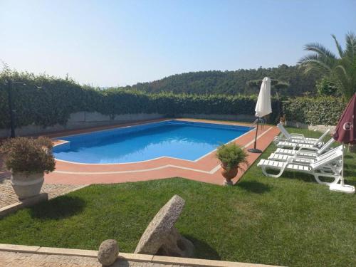 a swimming pool with two lawn chairs and an umbrella at CASA DO LAGAR in Agilde