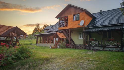 une maison en bois dans une cour avec un coucher de soleil en arrière-plan dans l'établissement Zatishok Bilya Richky, à Pilipets