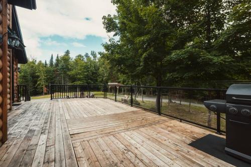 a wooden deck with a black fence and trees at Chalet Bonheur -Rustique- Pet friendly in Rivière-Rouge