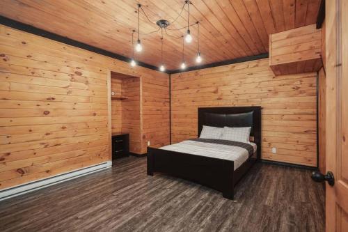 a bedroom with a bed in a wooden wall at Chalet Bonheur -Rustique- Pet friendly in Rivière-Rouge