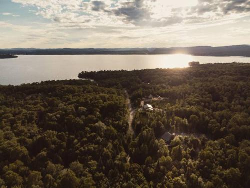 an aerial view of a forest with the sun setting over a lake at Chalet Bonheur -Rustique- Pet friendly in Rivière-Rouge