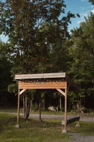 a wooden structure sitting in the grass in a park at Chalet Bonheur -Rustique- Pet friendly in Rivière-Rouge