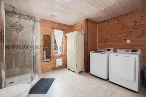 y baño con lavadora y ducha. en Chalet Bonheur -Rustique- Pet friendly en Rivière-Rouge