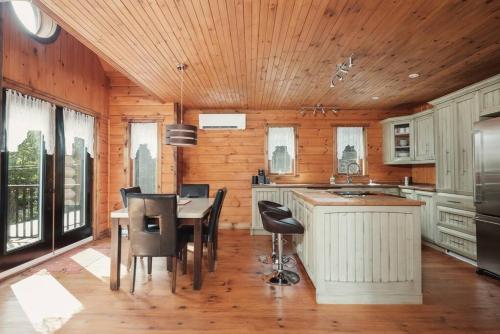 a kitchen with a wooden ceiling and a table and chairs at Chalet Bonheur -Rustique- Pet friendly in Rivière-Rouge