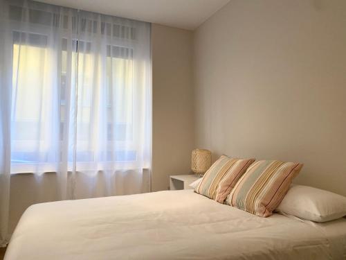 um quarto com uma cama branca e uma janela em Precioso apartamento junto a Casco Viejo em Bilbau
