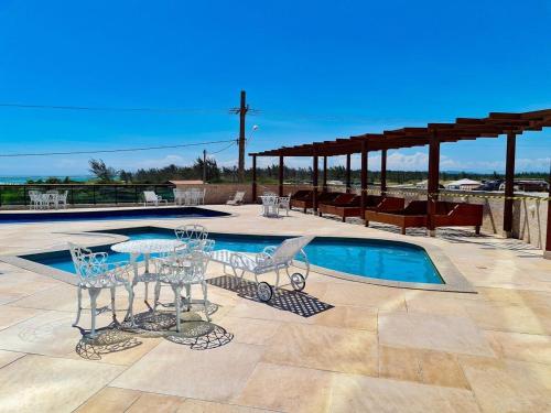 a patio with a table and chairs next to a pool at Arraial do Cabo. Cobertura Espetacular c Vista Mar in Arraial do Cabo