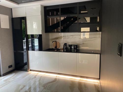 a kitchen with white cabinets and black appliances at Slow Time in Morąg
