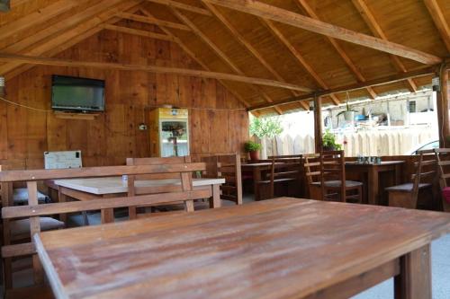 a restaurant with wooden tables and chairs and a television at Guesthouse Skender Selimaj in Valbonë
