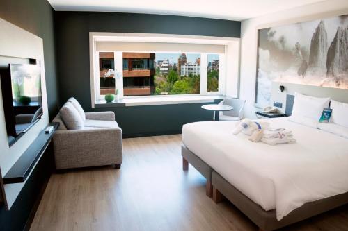 1 dormitorio con cama, sofá y ventana en Novotel Santiago Vitacura, en Santiago