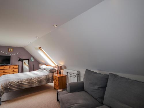 a living room with a couch and a bed at Ridge End Cottage in Kilmaluag