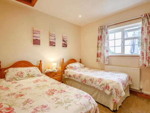 a bedroom with two beds and a window at 2 Black Horse Cottages in Pentraeth