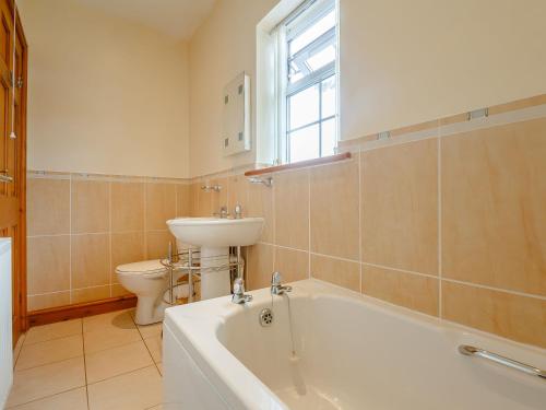 a bathroom with a tub and a sink and a toilet at 2 Black Horse Cottages in Pentraeth