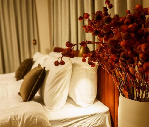 a bed with white pillows and a vase with a plant at שירת צפת in Safed