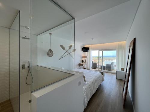 a bedroom with a glass shower and a bed at Alojamento White Rose Boutique in Zambujeira do Mar