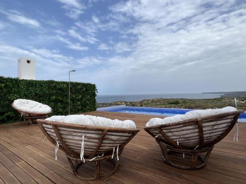 una terrazza con 2 sedie e una piscina di Alojamento White Rose Boutique a Zambujeira do Mar