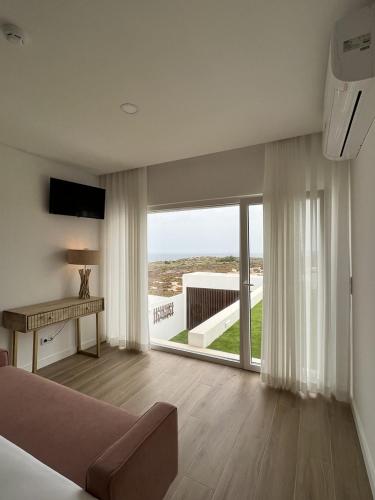 a living room with a couch and a large window at Alojamento White Rose Boutique in Zambujeira do Mar