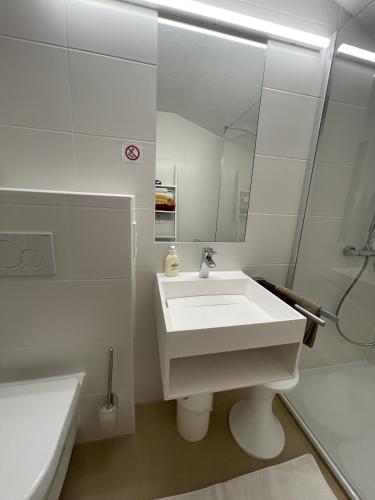 a white bathroom with a sink and a mirror at Fewo 2 am Auweg in Hirschegg