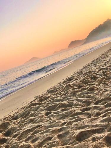 a sandy beach with the ocean in the background at POUSADA MAORI Boiçucanga in Boicucanga