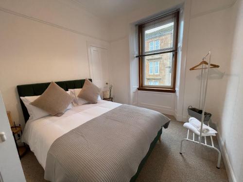 a bedroom with a large white bed with a window at A Shore Stay in Gourock