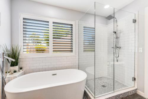a white bathroom with a tub and a glass shower stall at Poolside Getaway in Scottsdale