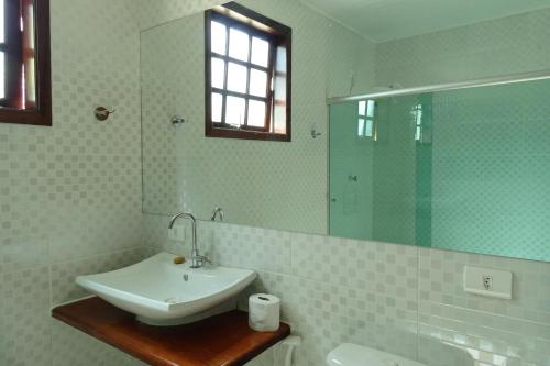 Un baño blanco con lavabo y espejo. en Refúgio Melissa, en Campos do Jordão