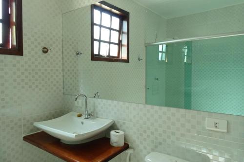 Baño blanco con lavabo y espejo en Refúgio Melissa, en Campos do Jordão