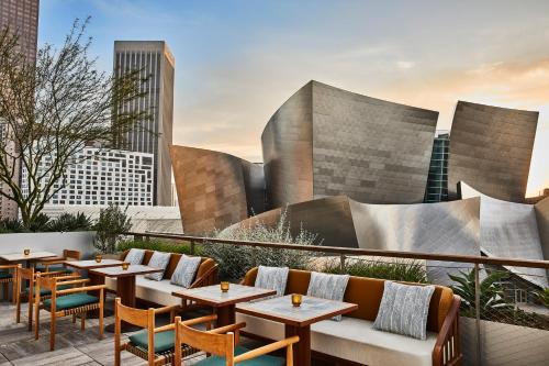 a rooftop patio with tables and chairs and buildings at Conrad Los Angeles in Los Angeles