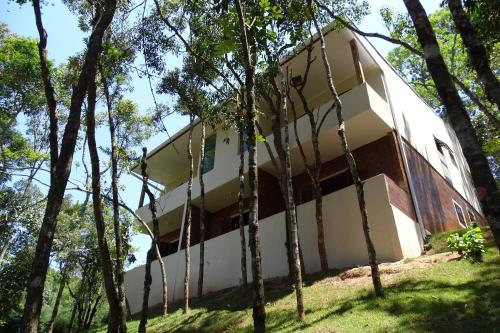 una casa en el bosque con árboles alrededor en Refúgio Melissa, en Campos do Jordão