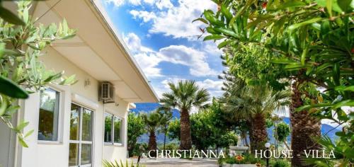 a house with palm trees in front of a building at Christianna House -Villa in Georgioupolis