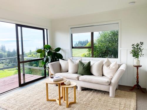 sala de estar con sofá blanco y ventanas grandes en The Ridge en Burnt Pine