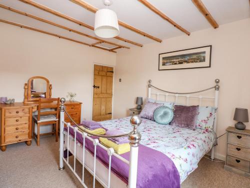 a bedroom with a bed and a desk and a chair at Holly Cottage in Swaffham