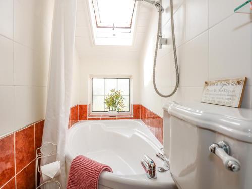 a bathroom with a tub and a sink and a window at Holly Cottage in Swaffham