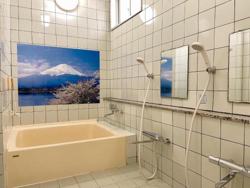 a bathroom with a tub and a picture of a mountain at 和みの宿　おりがみ in Nagasaki