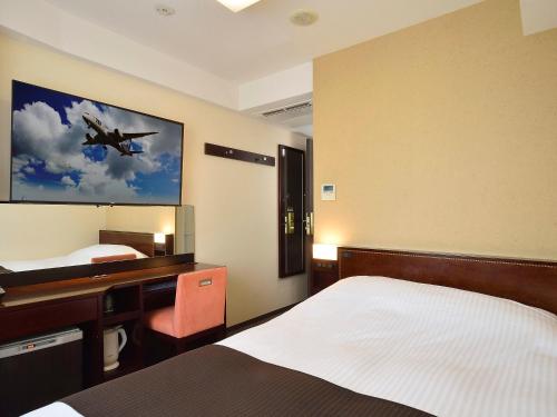 1 dormitorio con escritorio y una pintura de avión en la pared en APA Hotel Haneda Anamori Inari Ekimae, en Tokio