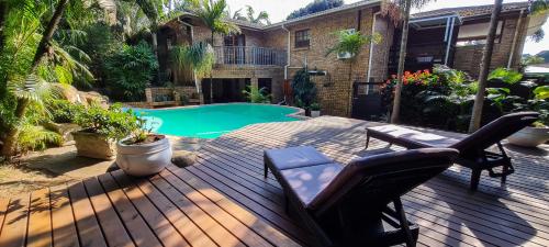 a deck with chairs and a swimming pool at Annas Bed and Breakfast in St Lucia