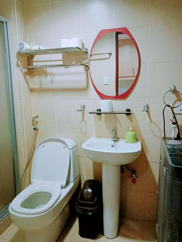 een badkamer met een toilet, een wastafel en een spiegel bij 14d mosaic staycation in Manilla