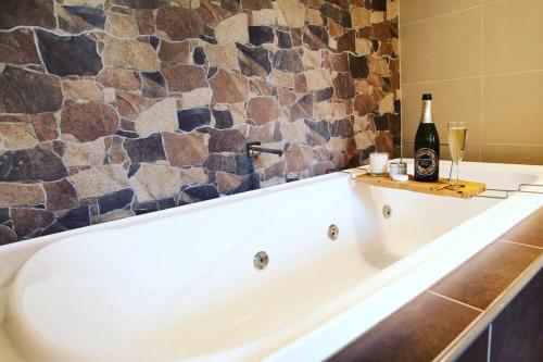 a bath tub with a bottle of wine and two glasses at Hickey Vale Farm Lodge Pet Friendly in Broadford