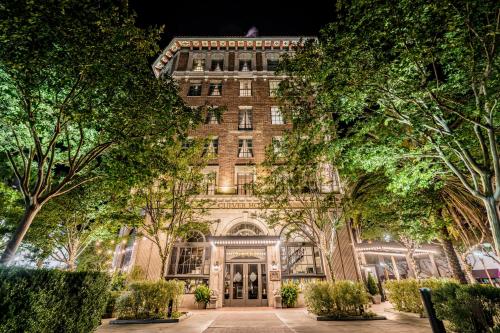 an old brick building with trees in front of it at The Culver Hotel in Los Angeles