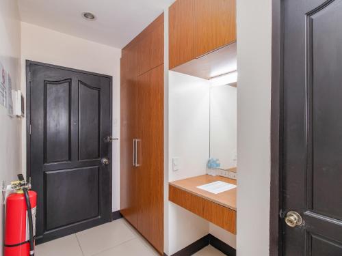 a bathroom with a black door and a red suitcase at Main Hotel & Suites in Cebu City