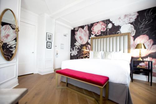 a bedroom with a large bed with a red bench at The Culver Hotel in Los Angeles