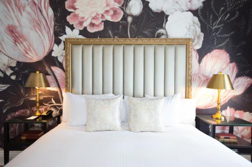 a bedroom with a bed with white pillows and a floral wallpaper at The Culver Hotel in Los Angeles