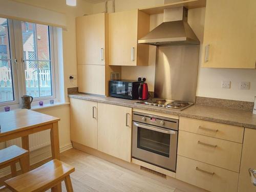 a kitchen with a stove and a microwave at Dunes Walk Cottage in Camber