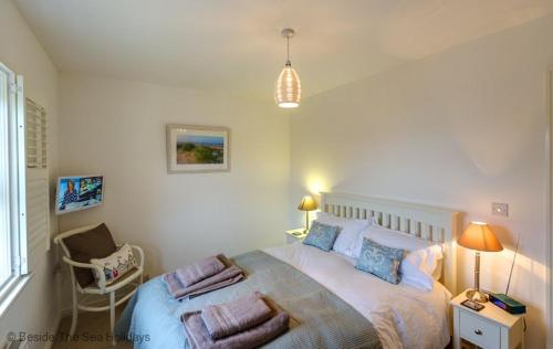 een slaapkamer met een groot bed met kussens erop bij Mallow Cottage in Camber