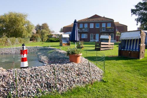 a yard with a house and a lighthouse on a rock wall at Zur kleinen Meerjungfrau in Dranske