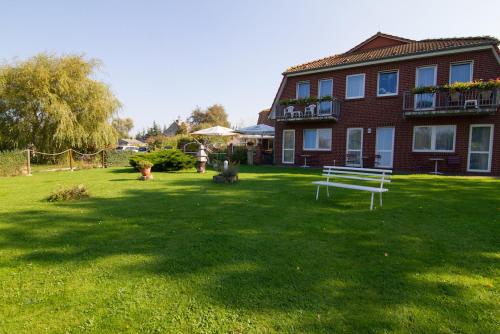 a yard with a house and a bench in the grass at Zur kleinen Meerjungfrau in Dranske