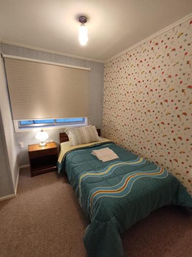 1 dormitorio con 1 cama en una habitación con pared en Se arrienda cómoda casa por día, en Punta Arenas