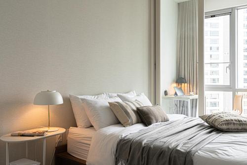a white bedroom with a large bed and a window at Urbanstay Dongtan in Hwaseong