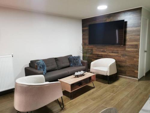 ein Wohnzimmer mit einem Sofa und einem TV in der Unterkunft Casa Especial in Puerto Natales